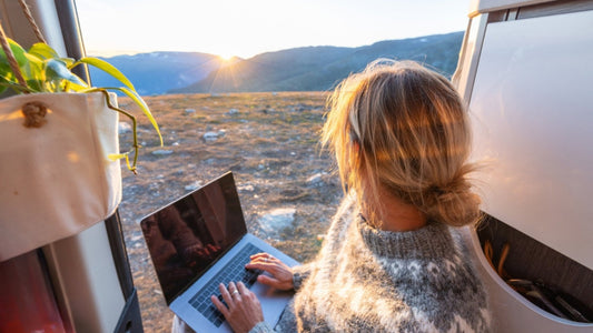 A woman working from her van while admiring a sun rise