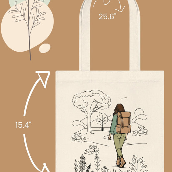 Introducing The Adventurous Woman Tote Bag, featuring a captivating hiking scene illustration. It has a 25.6-inch strap, is 15.4 inches high, and 14.6 inches wide. The design includes a brown background with abstract plant motifs in the corners, making it an ideal choice for eco-conscious and sustainable travel enthusiasts.